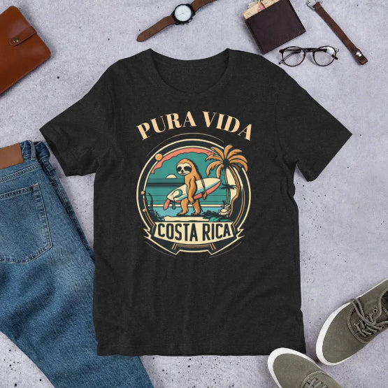 👉 "Unisex t-shirt with a playful sloth riding a surfboard, embodying Costa Rica’s relaxed beach culture and surfing vibes."